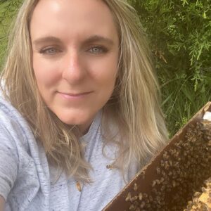 Buzzy Meadows' Proprietor, Bobby Kay Redondo next to a box of bees